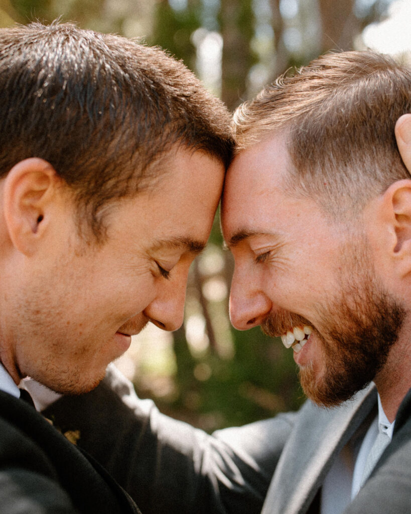 Groom and groomsman touching foreheads