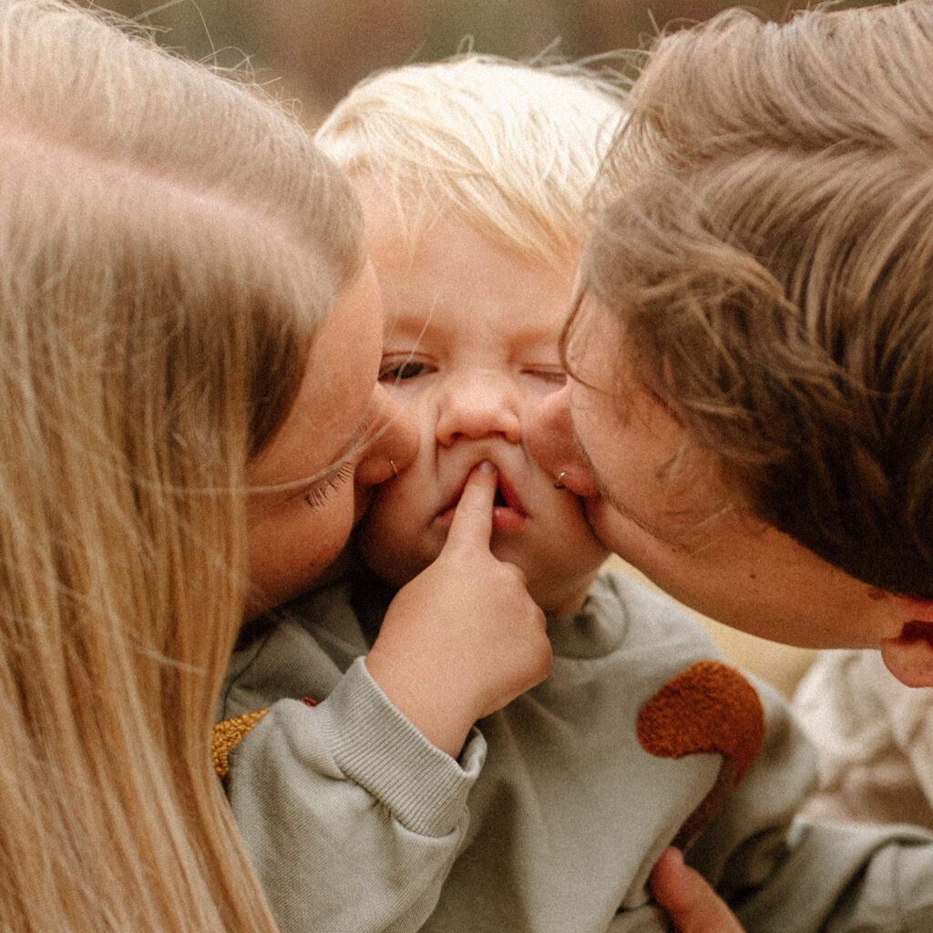 Mother and father kissing their toddler