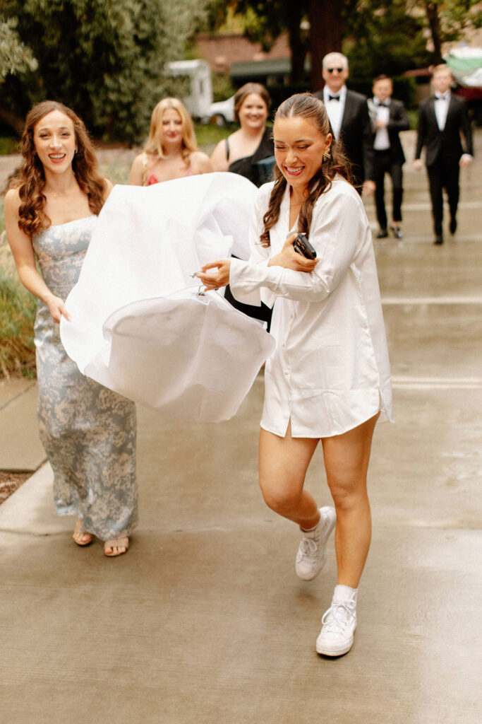 Bride and bridesmaids carrying wedding dress inside