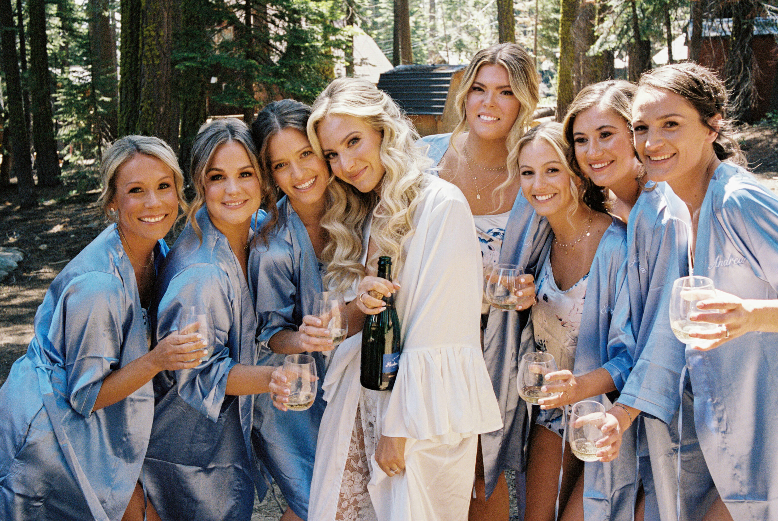 bride and bridesmaids pose together with their champagne 