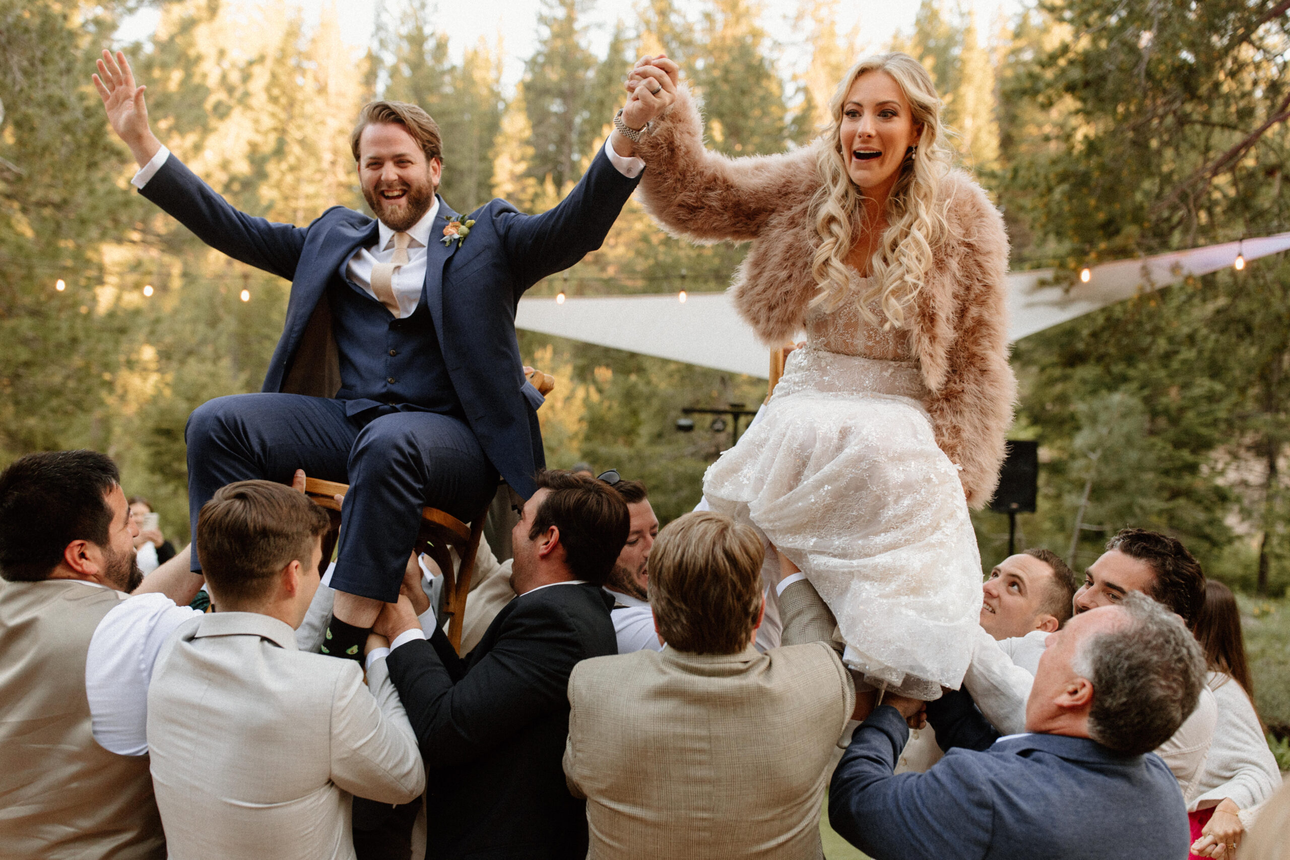 bride and groom get lifted in air by their guests