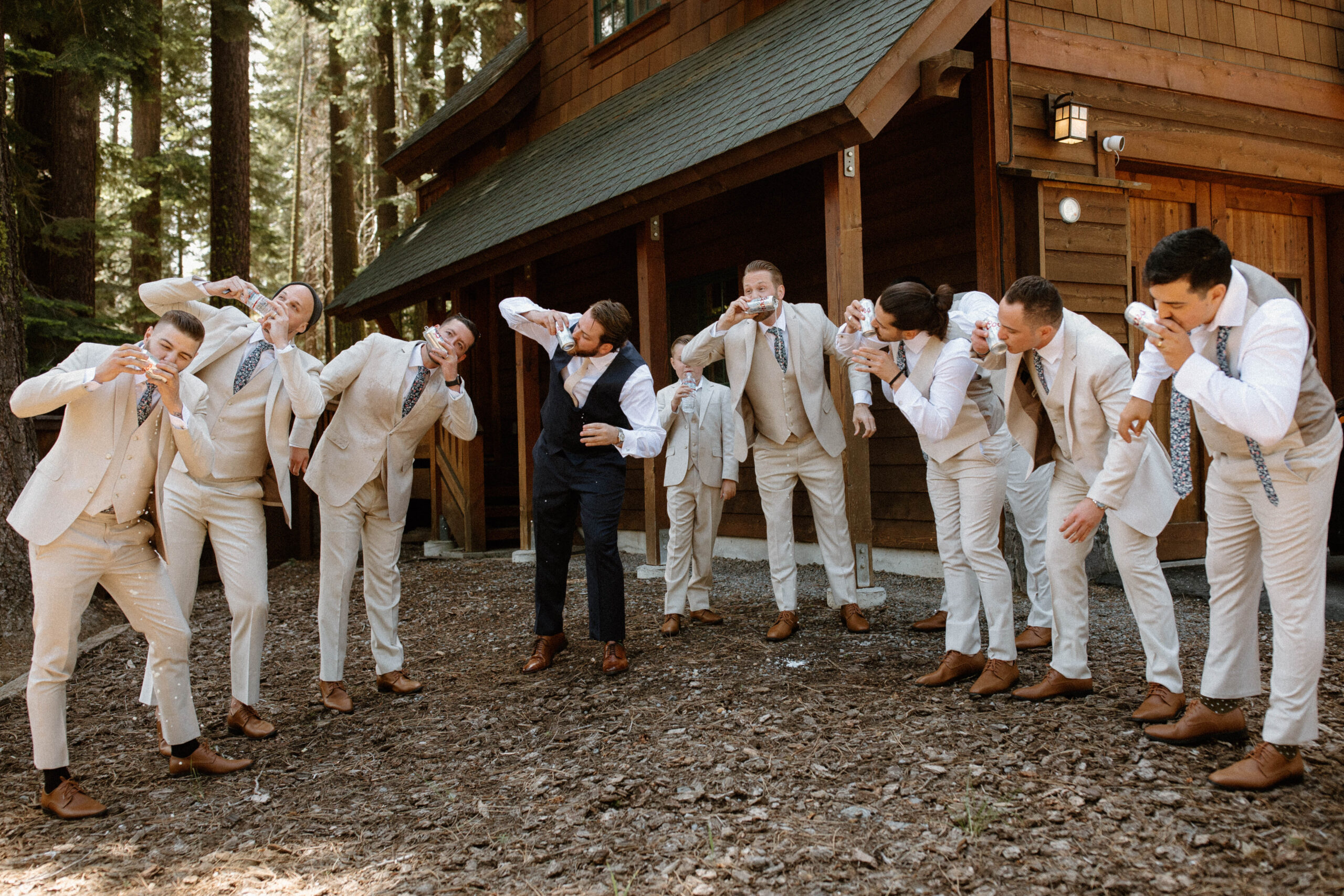 groomsmen celebrate with the groom as they all shotgun a beer together 