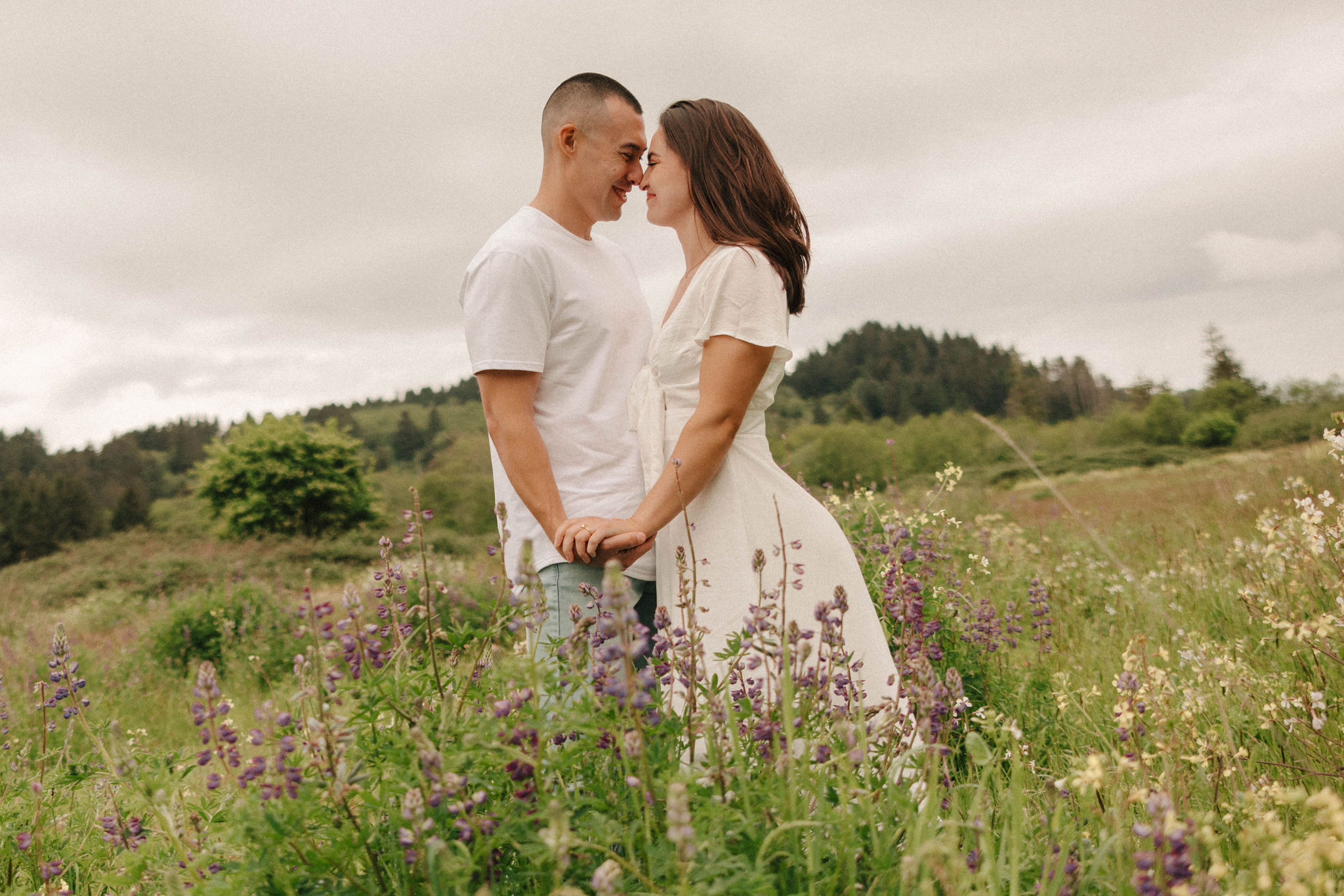 couple pose in a wildflower field together during their Redwood Forest engagement photoshoot