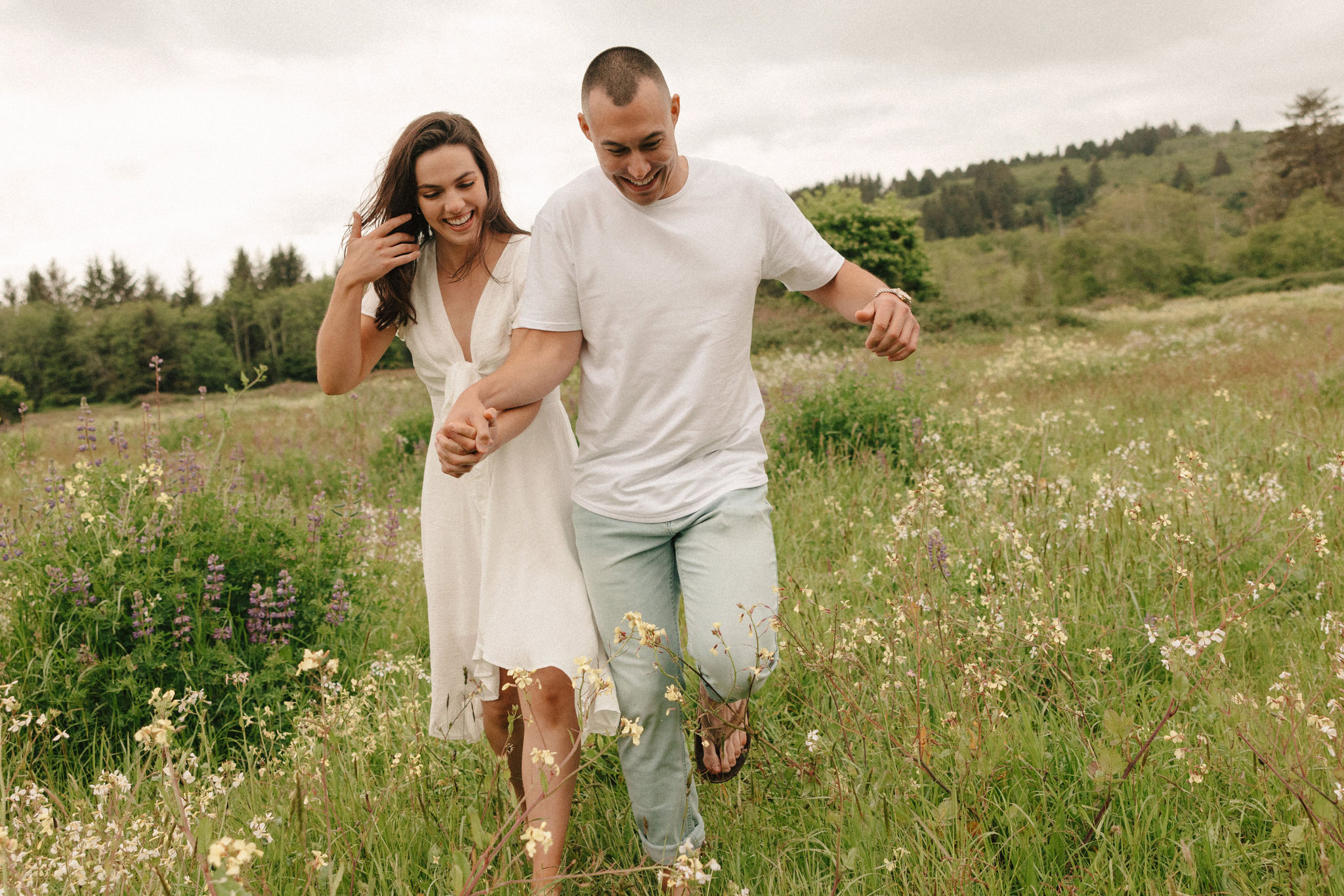 couple pose in a wildflower field together during their Redwood Forest engagement photoshoot