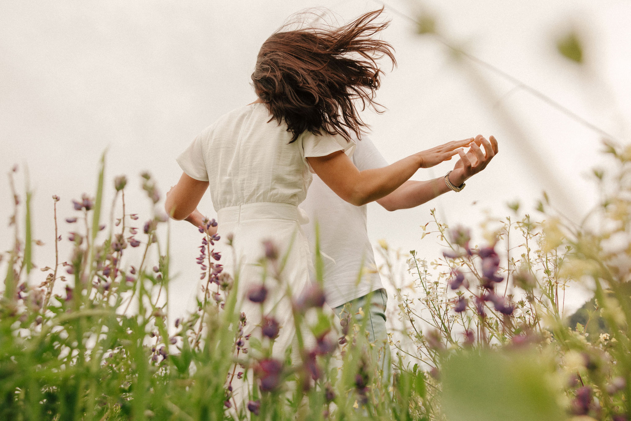 couple pose in a wildflower field together during their Redwood Forest engagement photoshoot