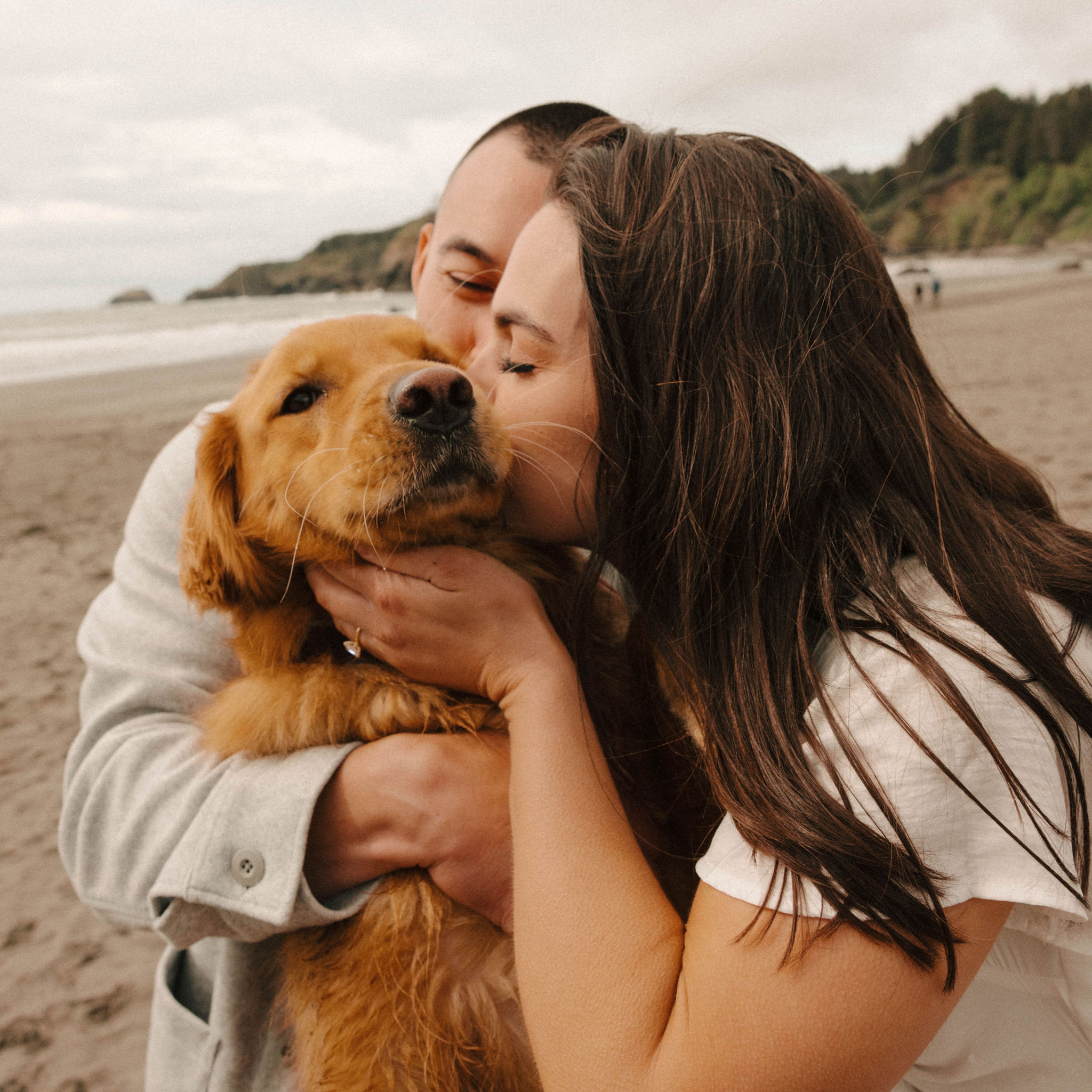 couple pose together on the California coast their beautiful dog