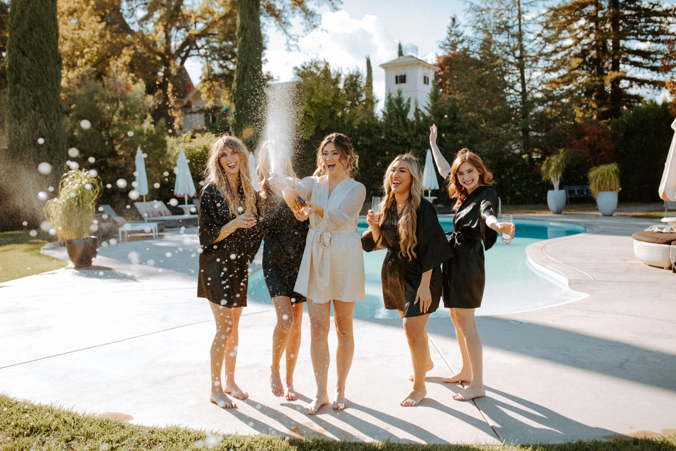 bridesmaids pose together by the pool