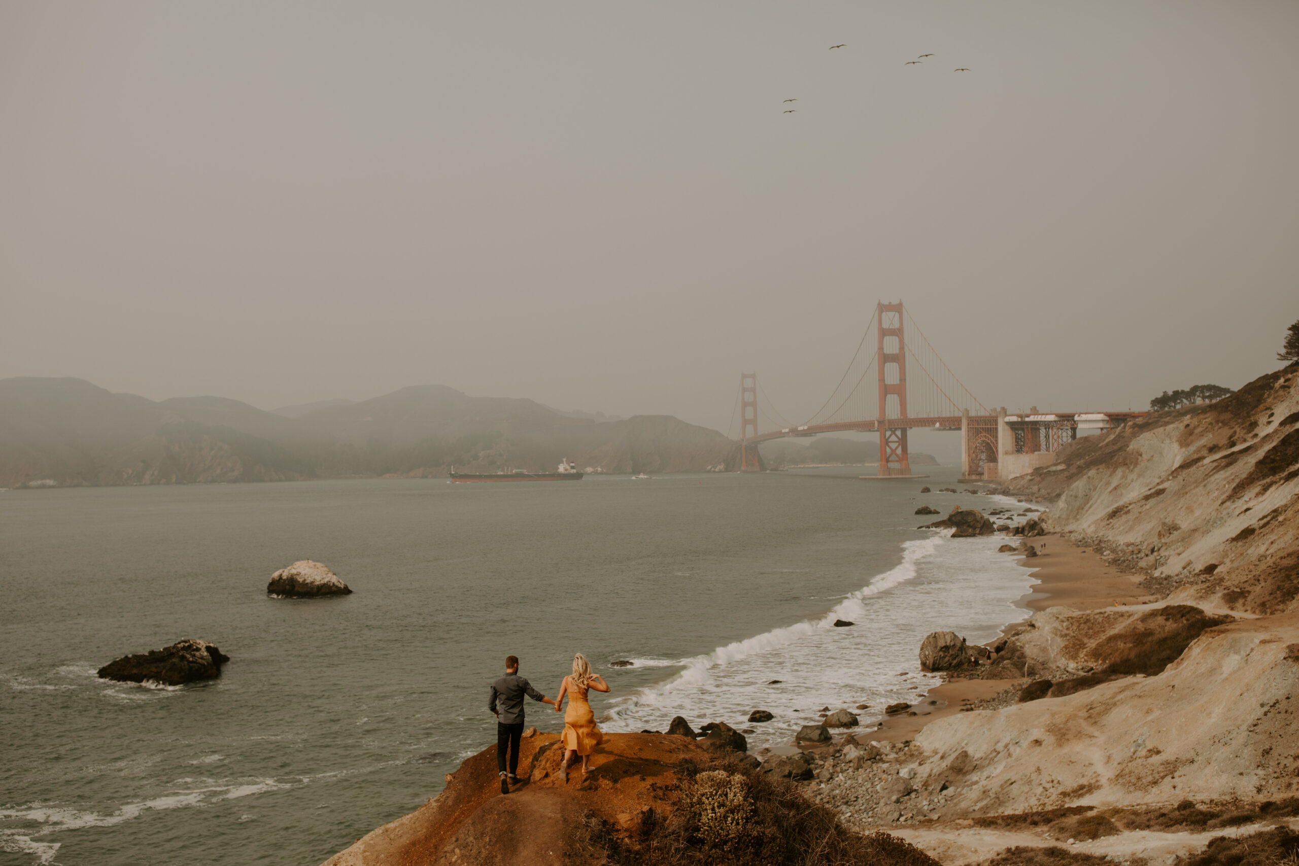 beautiful couple share an intimate moment during their candid California engagement photoshoot with the golden gate bridge in the background