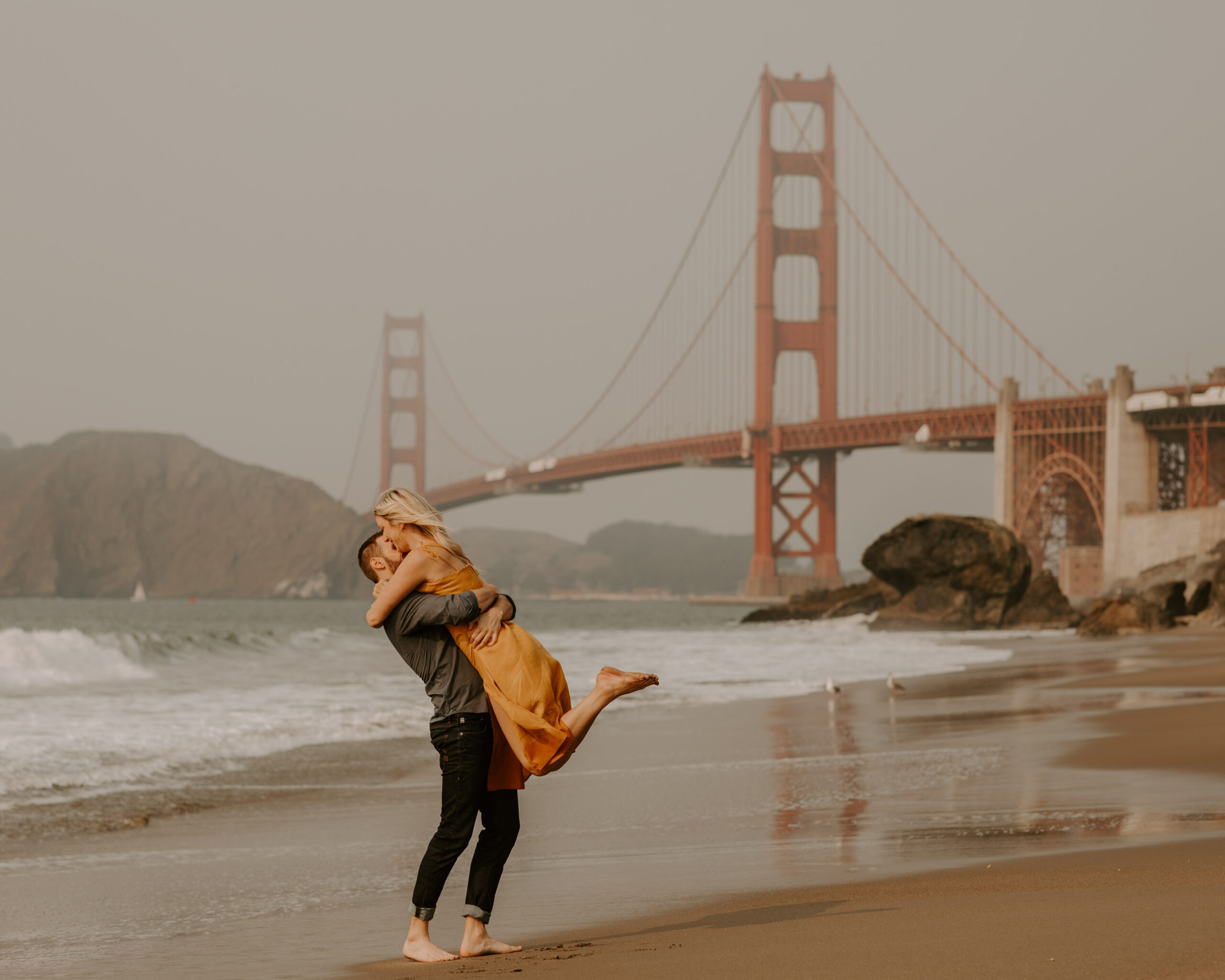 beautiful couple share an intimate moment during their candid California engagement photoshoot with the golden gate bridge in the background